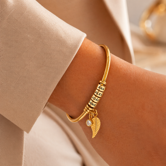 Gold family name bracelet with angel wing charm on wrist